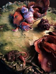 close-up of resin encased mixed media assemblage of two doll-faced orange fish rising out of the water to see a beating heart