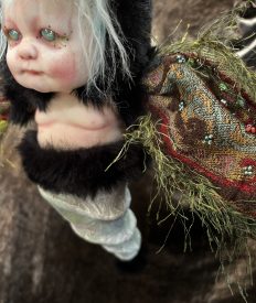 close-up chubby babydoll moth hybrid art doll hand-painted with tapestry wings and black fur, light blue, red and green
