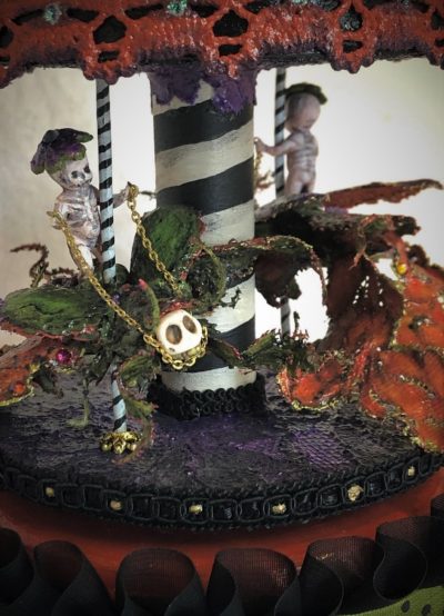 close-up of gothic striped carousel music box with tiny ghost skeletons riding bejeweled beetles black, orange, purple and green