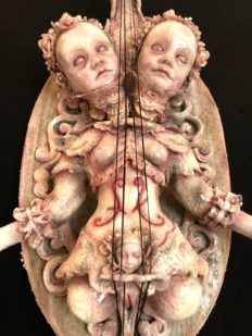 mixed media assemblage of two headed painted goth doll with violin strings