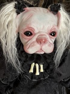 close-up hand painted dog-faced doll head with blond pigtails black dress bone necklace