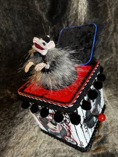mixed media assemblage jack in the box with a skull faced furry rat who pops out of the hand painted cranked box, black white and red with black pom poms