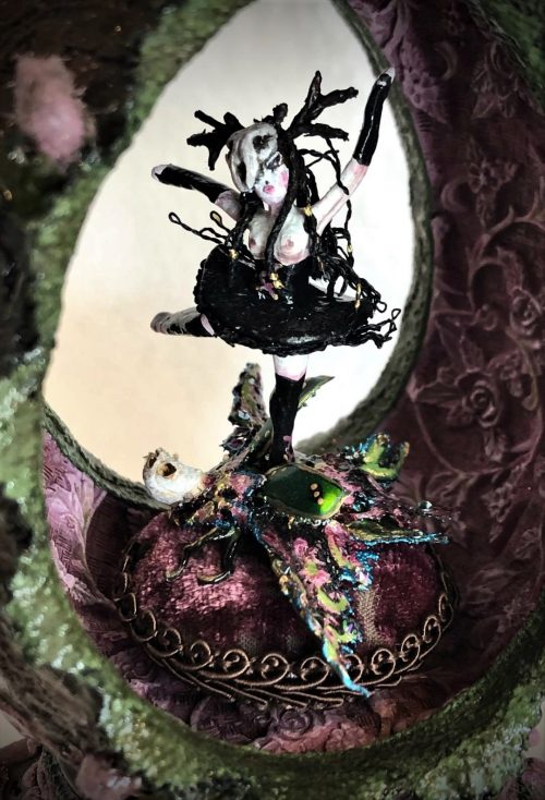 tiny gothic dancer wearing skull headdress and black tutu spins atop a bejeweled beetle in a velvety purple moss-covered egg music box
