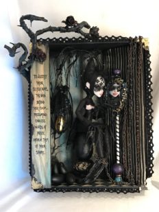 mixed media assemblage shadow box diorama with a repainted goth doll staring into a mirror and ignoring her black eggs