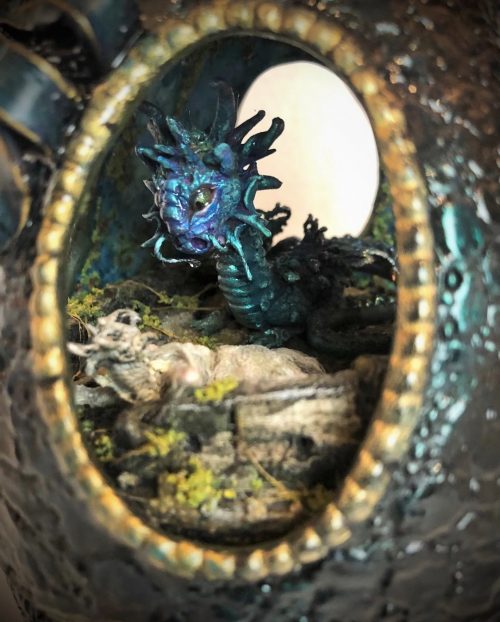 peek through oval window at green and blue fantasy dragon creature above lifeless maiden