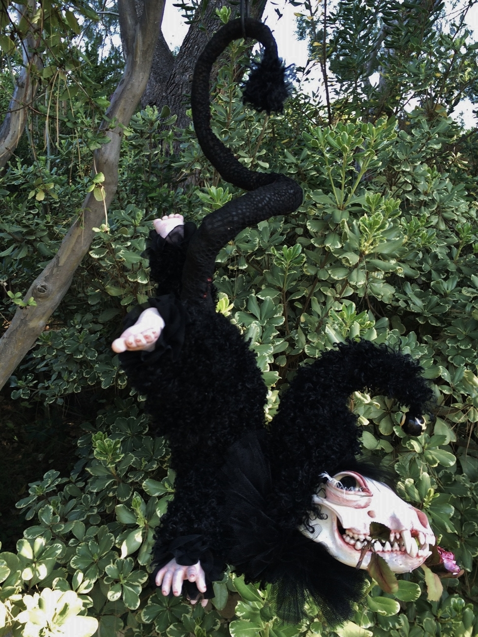long-hanging artdoll fantasy beast doll with painted racoon skull, curly black mohair fur covered body and vinyl doll feet