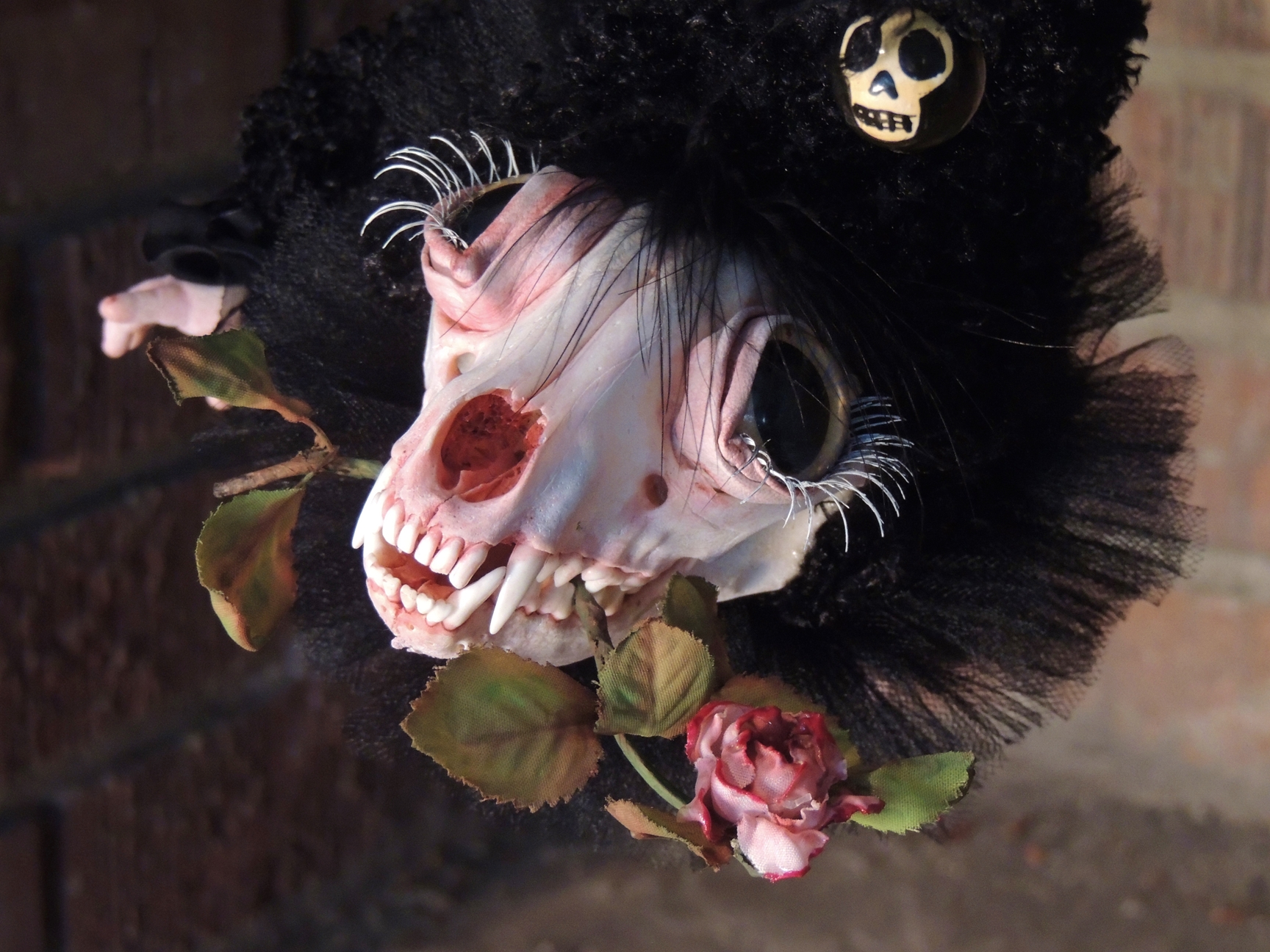 long-hanging artdoll fantasy beast doll with painted racoon skull, curly black mohair fur covered body and vinyl doll feet silk rose in his teeth