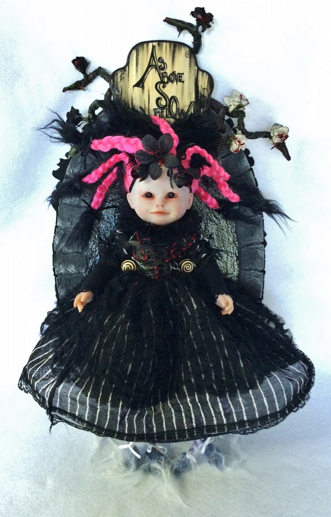 pale gothic artdoll with hot pink braids black eyes with no pupils and a black dress mounted on a carved hand-painted wooden plaque