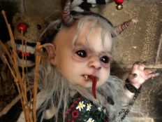 mixed media artdoll creepy evil babydoll elf with horns, black eyeballs, pointed elf ears, tongue sticks out, faux fur collar