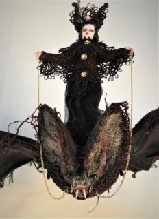 mixed media miniature gothic circus performer wearing black lace rides a lace-covered vintage toy bat.