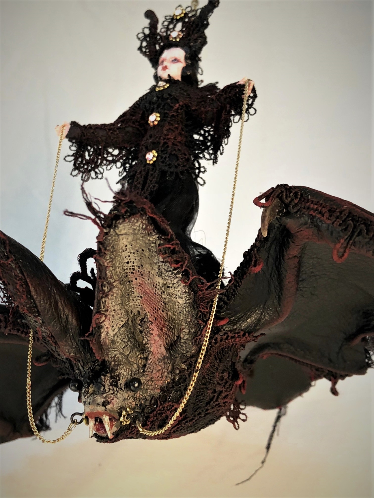 mixed media miniature gothic circus performer wearing black lace rides a lace-covered vintage toy bat.