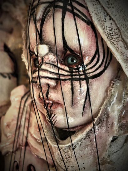 close up of repainted goth doll face with strings over it