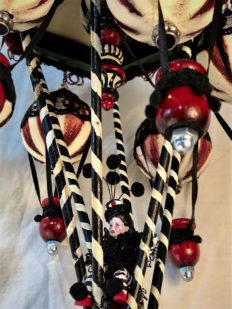 close-up red, black and white mixed media mobile striped miniature gothic circus performer rides a hot air balloon