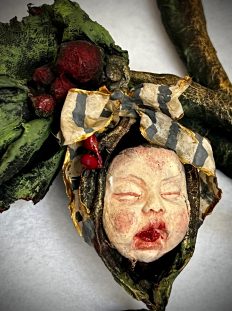 close-up handmade decorative element baby doll child head with holly mistletoe