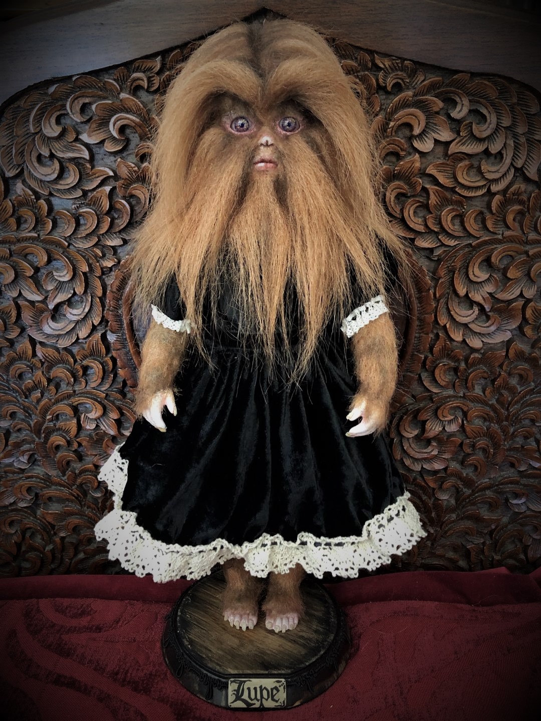 vintage-inspired werewolf artdoll with light brown fur covering her face, arms and legs dressed in black velvet dress trimmed with white lace standing on a wooden platform