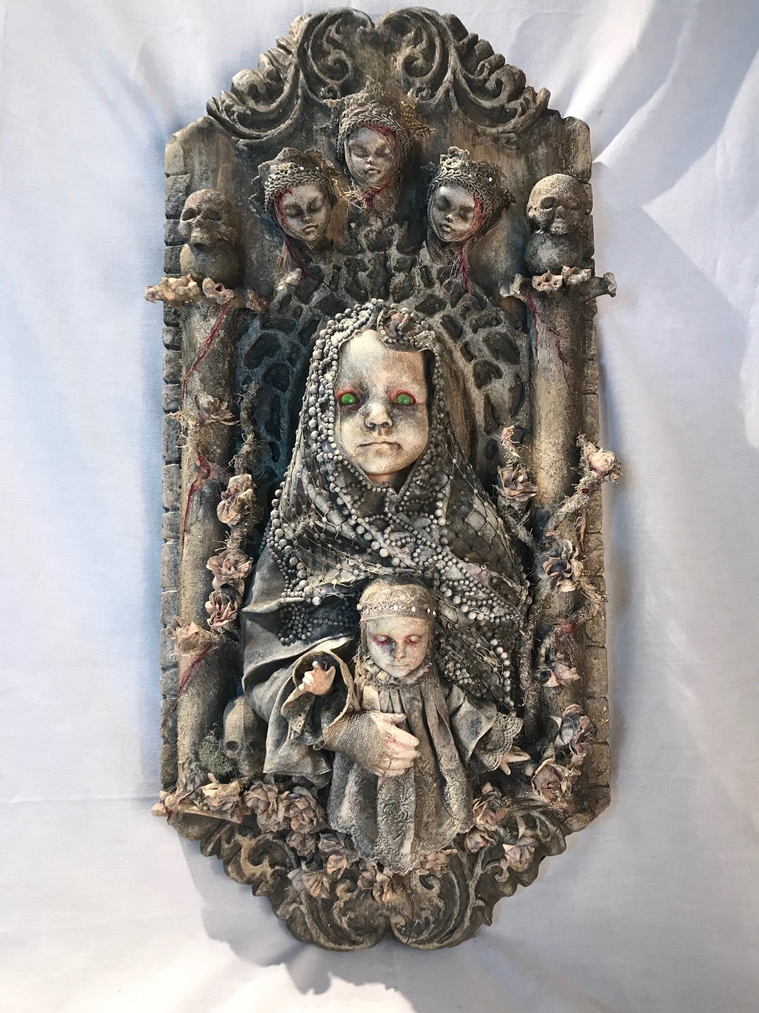 mixed media assemblage plaque repainted sainted robed baby doll holding a baby with the three fates above her