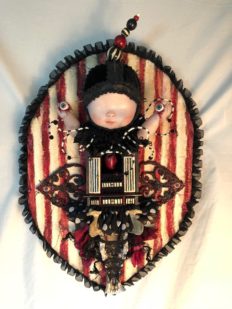 red, white and black striped mixed media gothic circus-themed artpiece of a doll holding her own eyeballs with a small cabinet holding a heart for her torso and bone on striped textile covered wooden board