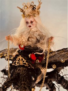 close-up mixed media miniature gothic white queen rides a black lace-covered vintage crowned toy queen bee