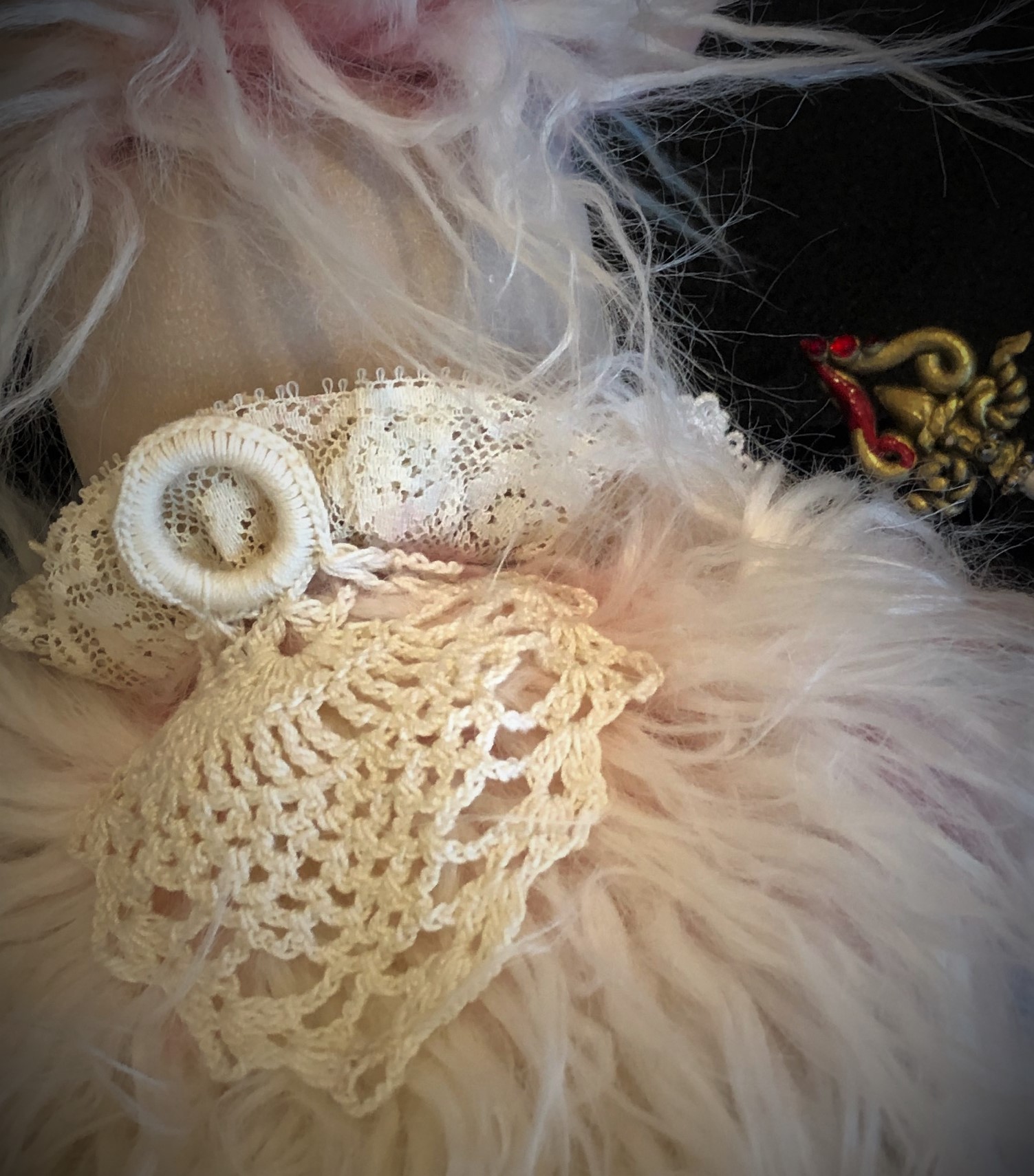 close-up detail of crocheted lace with ring to hang doll up with