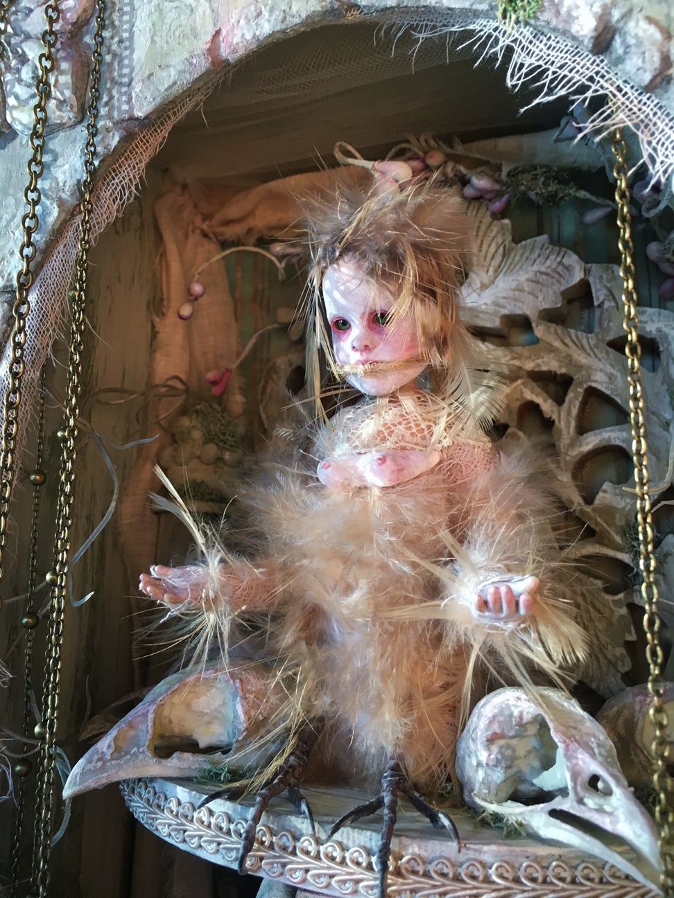 close-up mixed media assemblage artpiece shadowbox gothic feathered songbird artdoll with taxidermied bird feet in a hand-painted shadowbox on a platform with two bird skulls