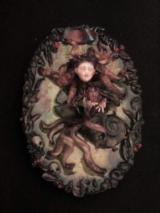 resin encased mixed media assemblage of a tiny tentacled, doll-faced creature floating in water holding a beating heart.