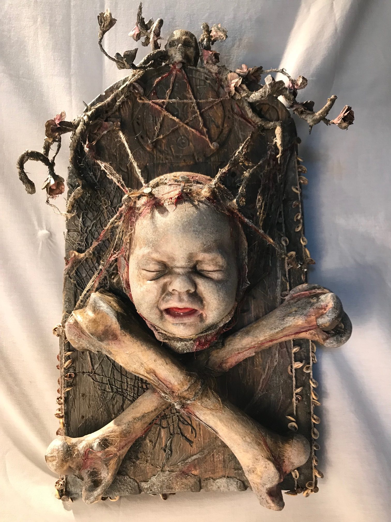 mixed media assemblage plaque crying baby doll head and crossbones pentagram