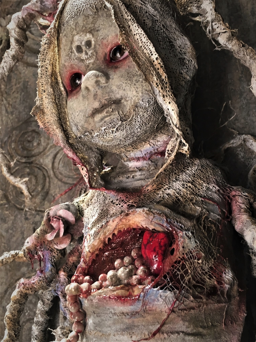 close up dark art mixed media assemblage sculpture of a macabre baby made with porcelain, bone & rope