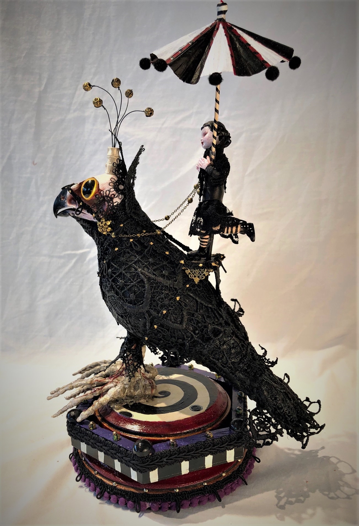 mixed media miniature gothic circus performer carrying a parasol rides a black lace-covered undead crow standing on painted wooden platform