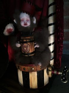 close-up of sculpted carnival circus monkey money collector doll sitting on a striped drum