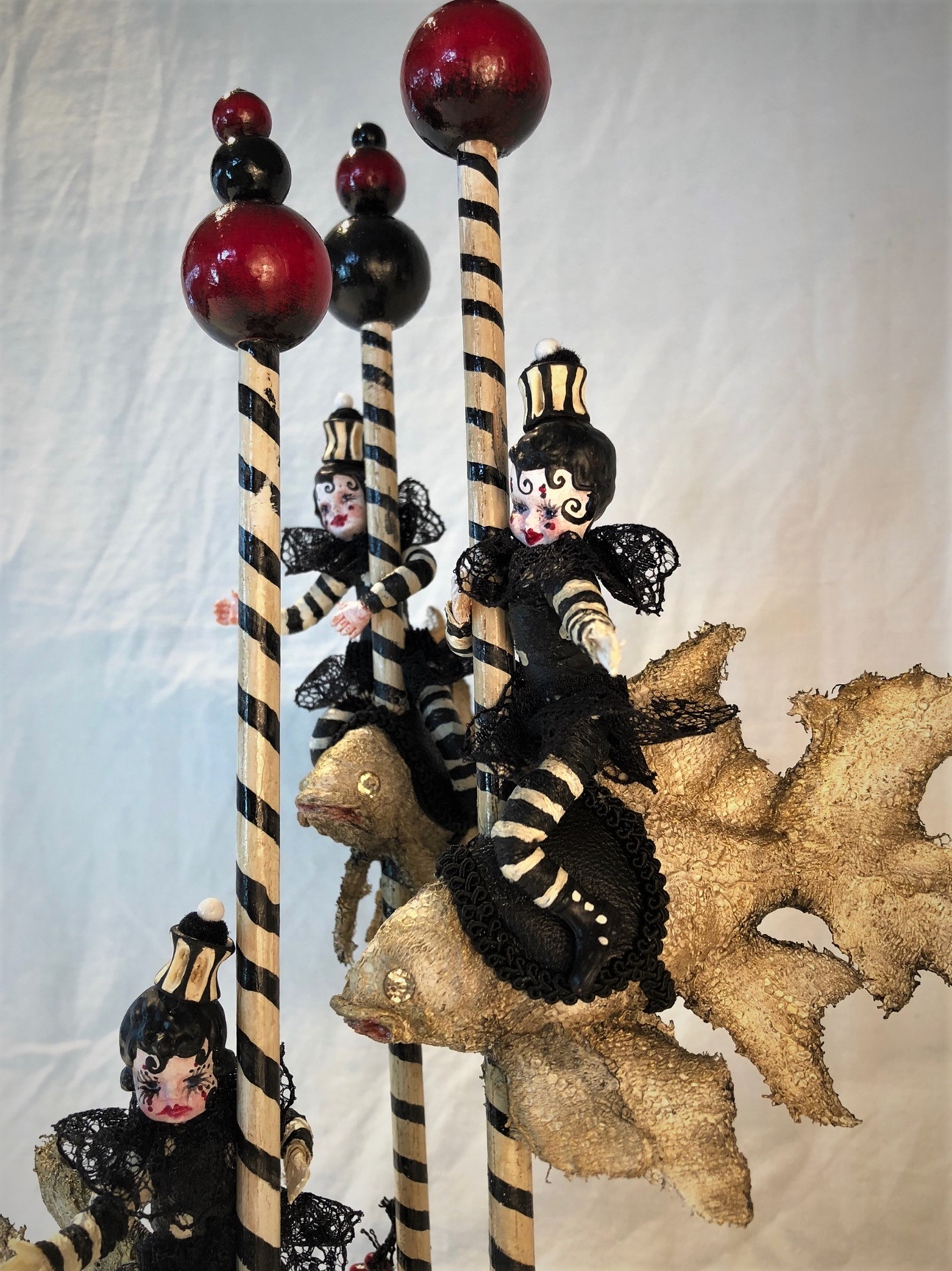 mixed media striped three miniature gothic sprites circus performers wearing black and white ride carousel fish in a garden of black roses