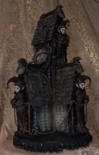 miniature darkened mixed media house with three goth elves chained in front of doors