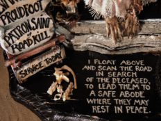 close-up of hand painted lettered poem on wood board with taxidermy rodent feet