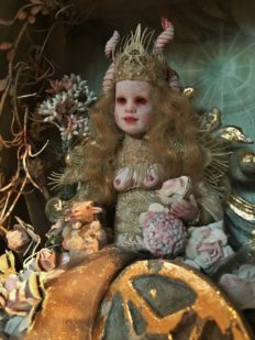 close-up of diorama shadowbox tableau of miniature blond crowned queen artdoll sitting with a pentacle