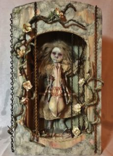 mixed media assemblage shadow box earth tones with an imprisoned goth repainted doll.