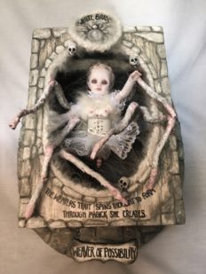 shadowbox mixed media assemblage of a ghostly gothic white spider themed doll with 8 legs pale with blond hair white corset and tutu she is inside a carved box with hand-painted wooden signs