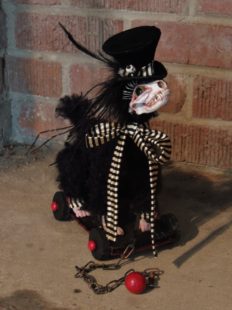 gothic victorian dandy black furry fantasy animal creature with real skull head and doll feet wearing a top hat and a black and white striped ribbon standing on a black and red wooden cart