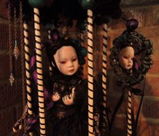 close-up of pale gothic artdoll wearing black looks at herself in a mirror