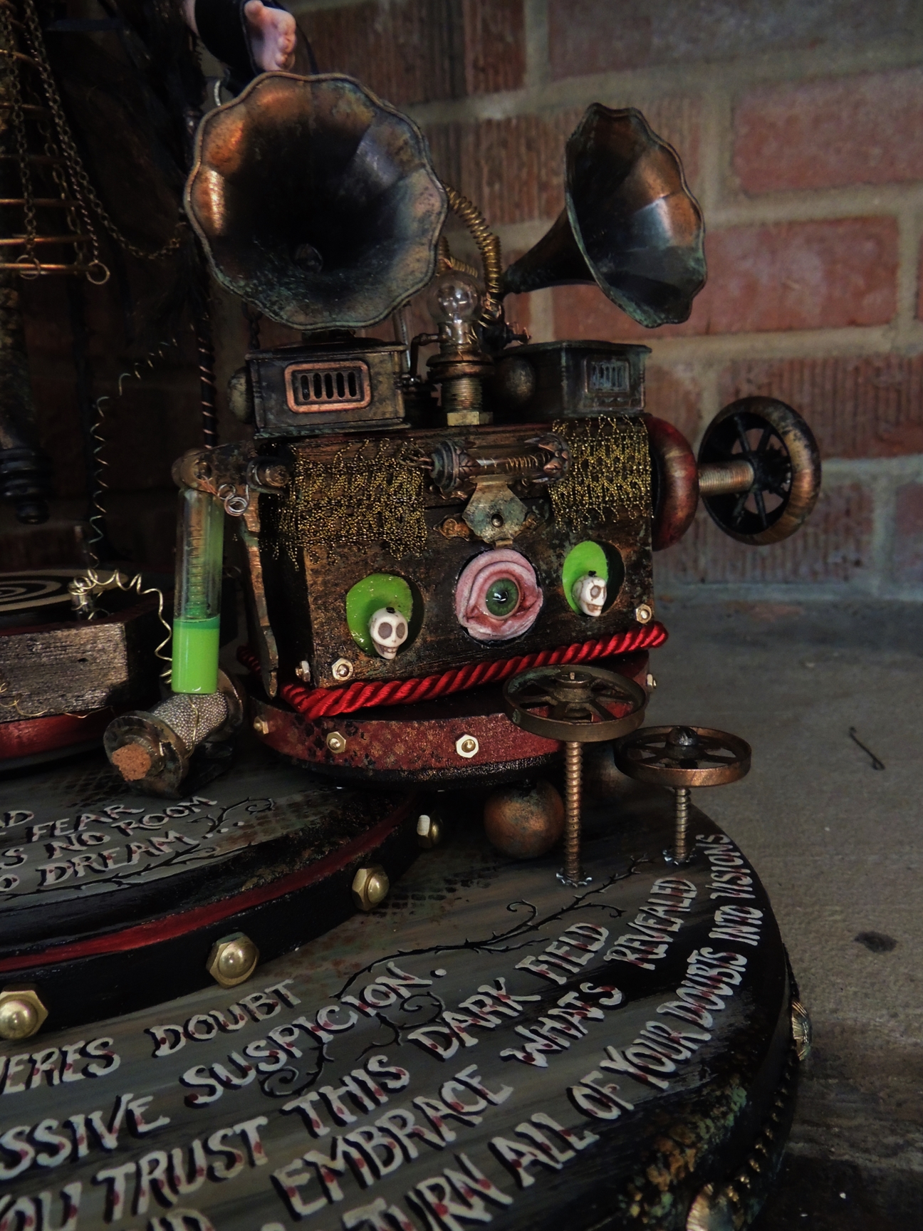 close-up of miniature phonograph steampunk dream machine contraption and painted poem lettering on wooden platform