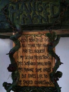 hand painted lettered sooden sign with verse on it surrounded by forest vines