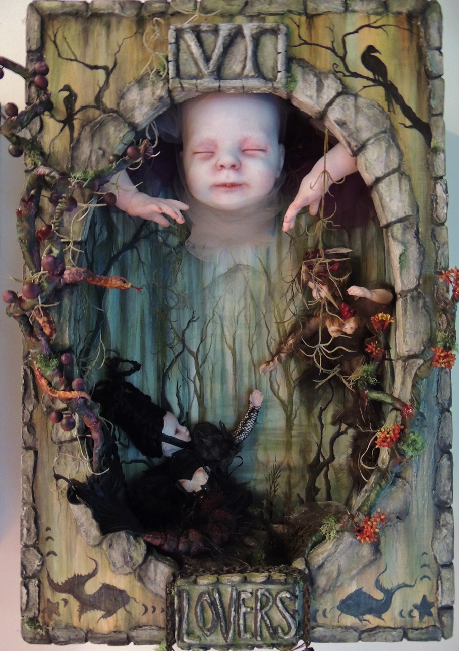miniature shadowbox diorama with two tiny gothic dolls reaching for each other in a hand painted forest setting with a bigger doll above them