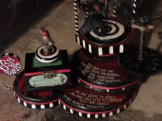 close-up of hand painted red and black circular platforms with hand lettered poetry and black and white spirals miniature trunk