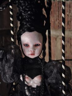 close-up pale gothic artdoll with plack puffed sleeves, black braided hair, black corset