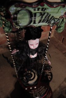 hand painted green and black sign above gothic mermaid art doll pale with black hair suspended above hand-painted red and black platforms music box