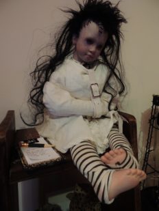 gothic artdoll with lobotomy scar, wild dark black hair, wears white straightjacket and black and white arm and leg warmers